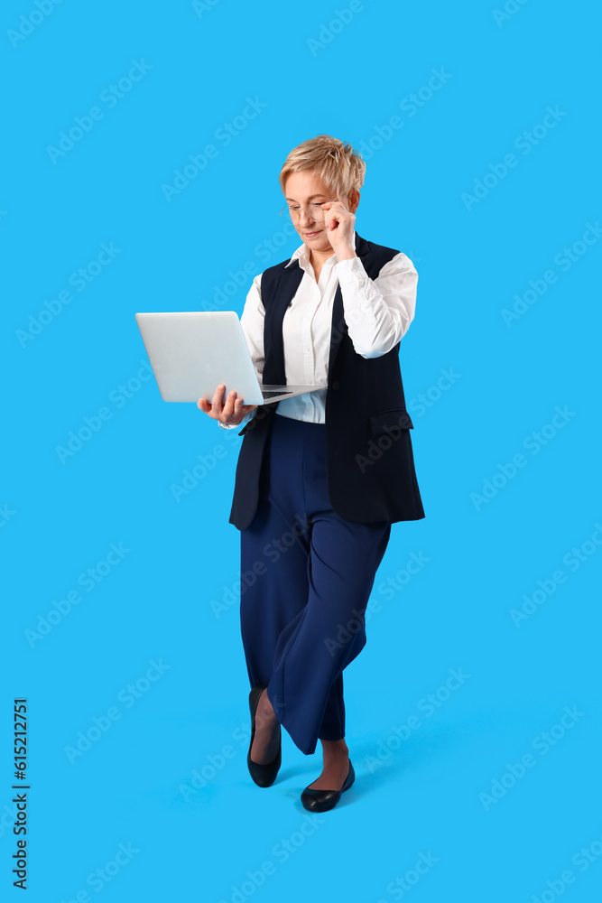 Mature female programmer working with laptop on blue background