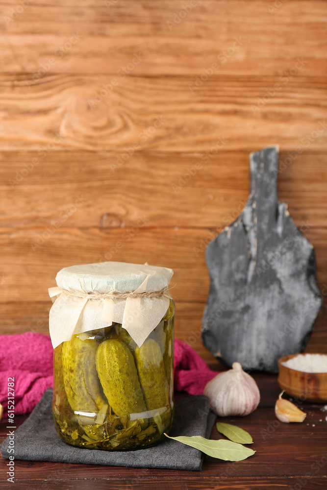 Jar with tasty canned cucumbers and spices on wooden table