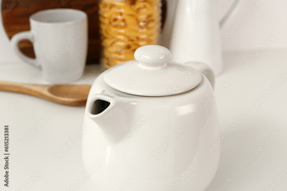 Composition with teapot, cup and different items on white table