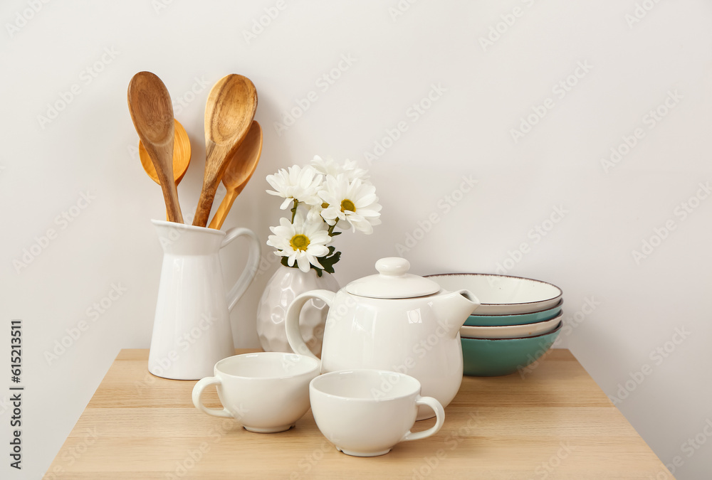 Composition with beautiful tea set, flowers and different kitchen stuff on wooden table