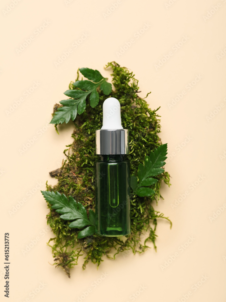 Bottle of cosmetic oil with plant twigs and moss on beige background