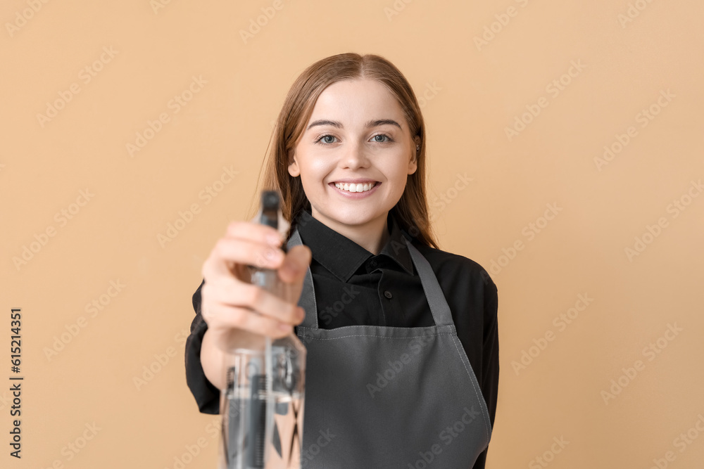 Female hairdresser with spray on beige background, closeup