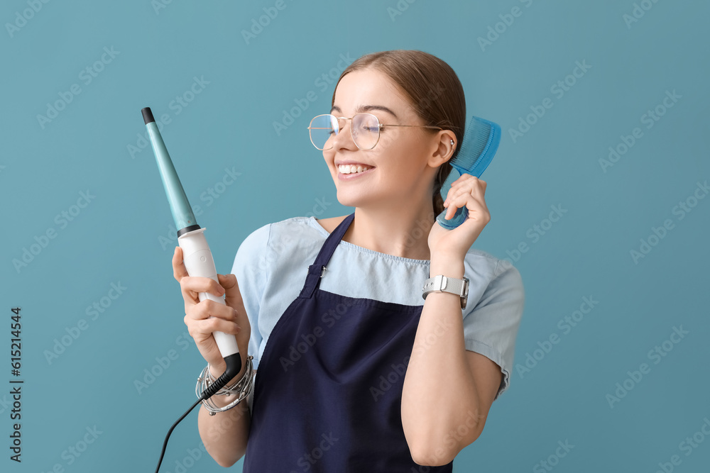 Female hairdresser with curling iron and comb on blue background