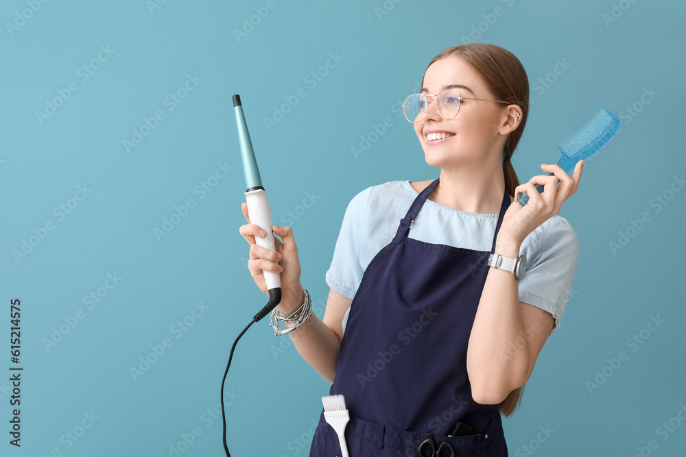 Female hairdresser with curling iron and comb on blue background