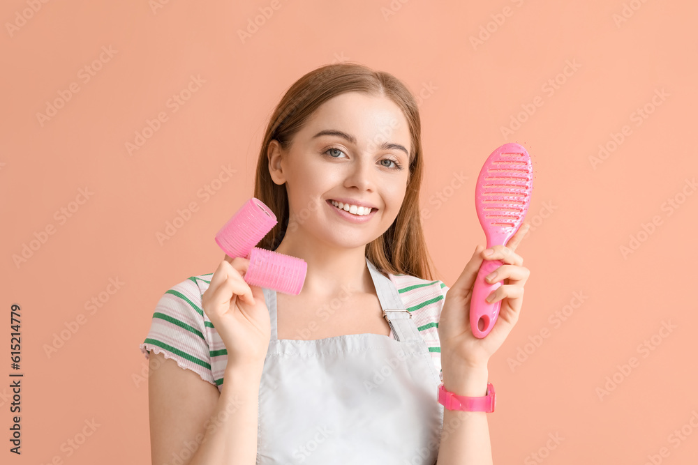 Female hairdresser with curlers and brush on pink background, closeup