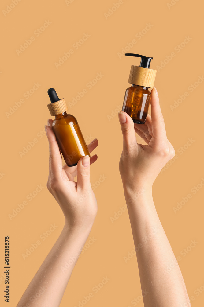 Hands holding cosmetic products on beige background