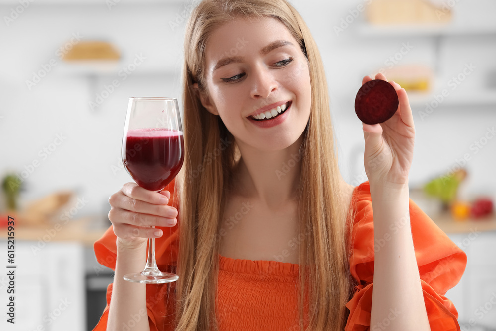 Young woman with glass of vegetable juice and beet in kitchen, closeup