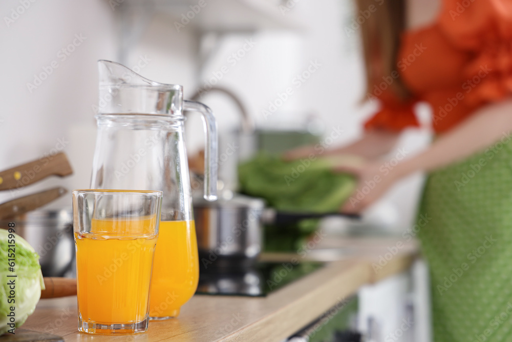 Glass and jug of juice on counter in kitchen, closeup