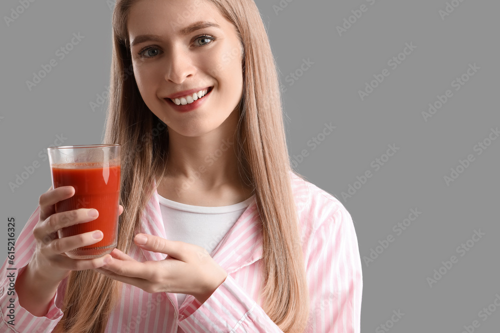 Young woman with glass of vegetable juice on grey background, closeup