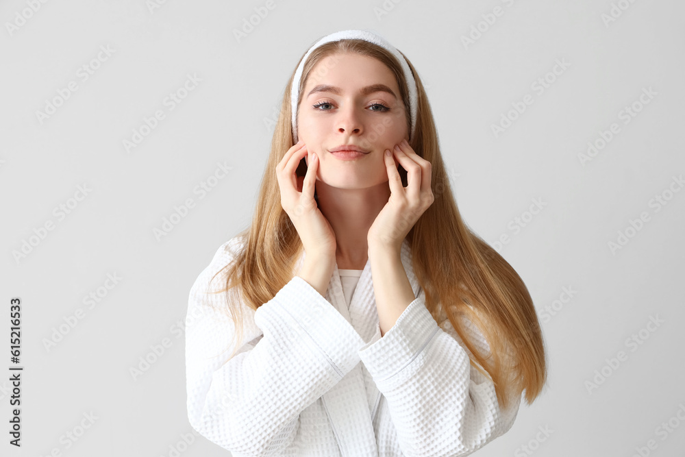 Young woman doing face building exercise on light background