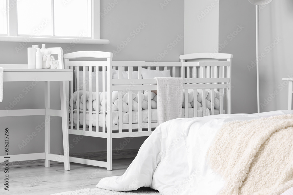 Baby crib in interior of light bedroom