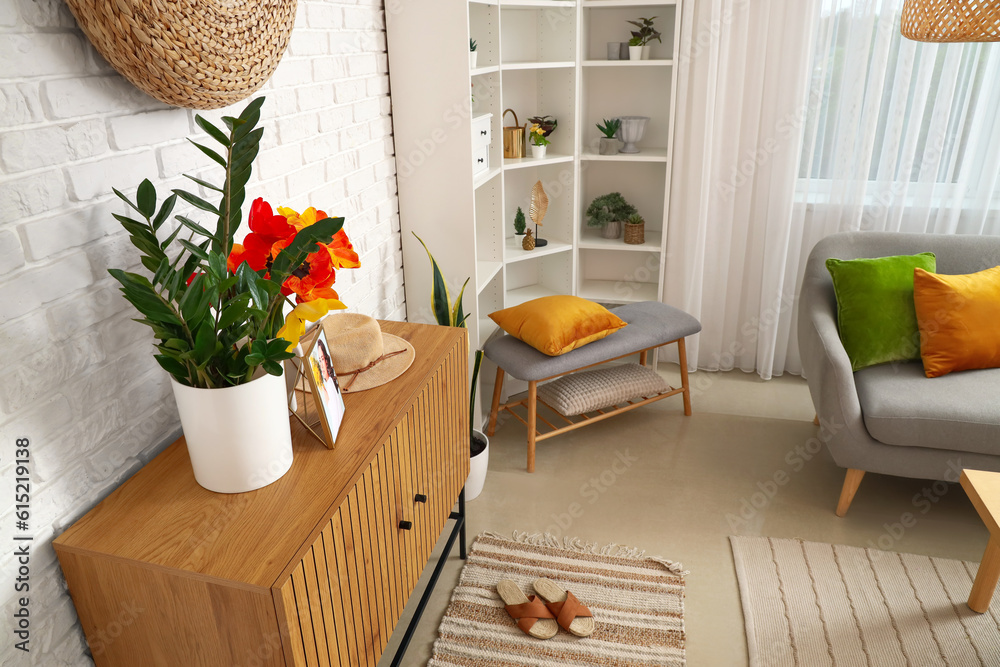 Vase with beautiful tulip flowers and houseplant on wooden cabinet in interior of living room