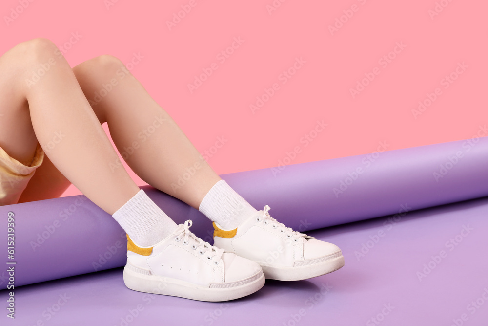 Female legs in stylish sneakers and socks on color background