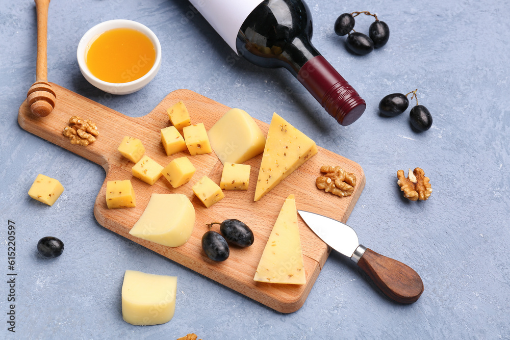 Wooden board with pieces of tasty cheese and honey on grey background