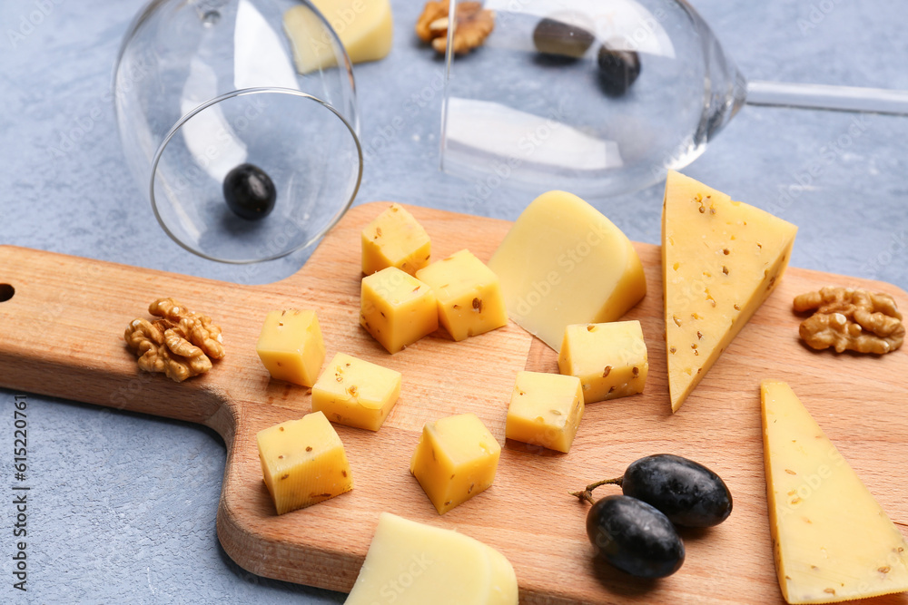 Wooden board with pieces of tasty cheese on grey background, closeup