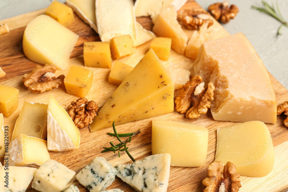 Wooden board with pieces of tasty cheese on table, closeup