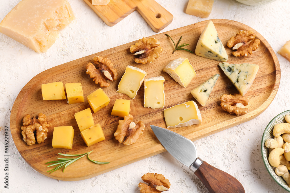 Wooden board with pieces of tasty cheese on light background