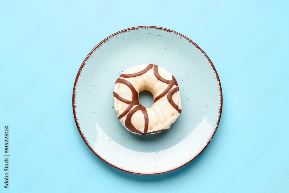 Plate with sweet donut on blue background