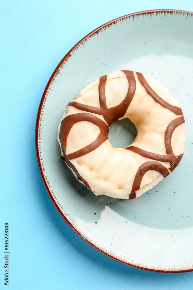 Plate with sweet donut on blue background