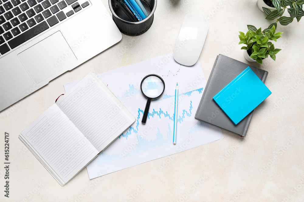 Magnifier with business charts on white table in office