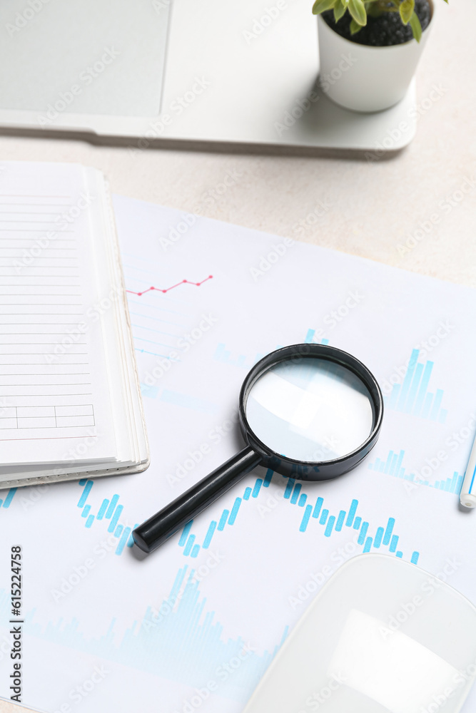 Magnifier with business charts on white table in office