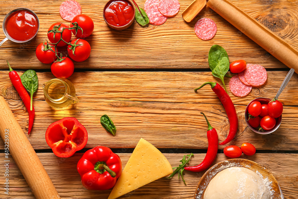 Frame made of fresh ingredients for preparing pizza on wooden background