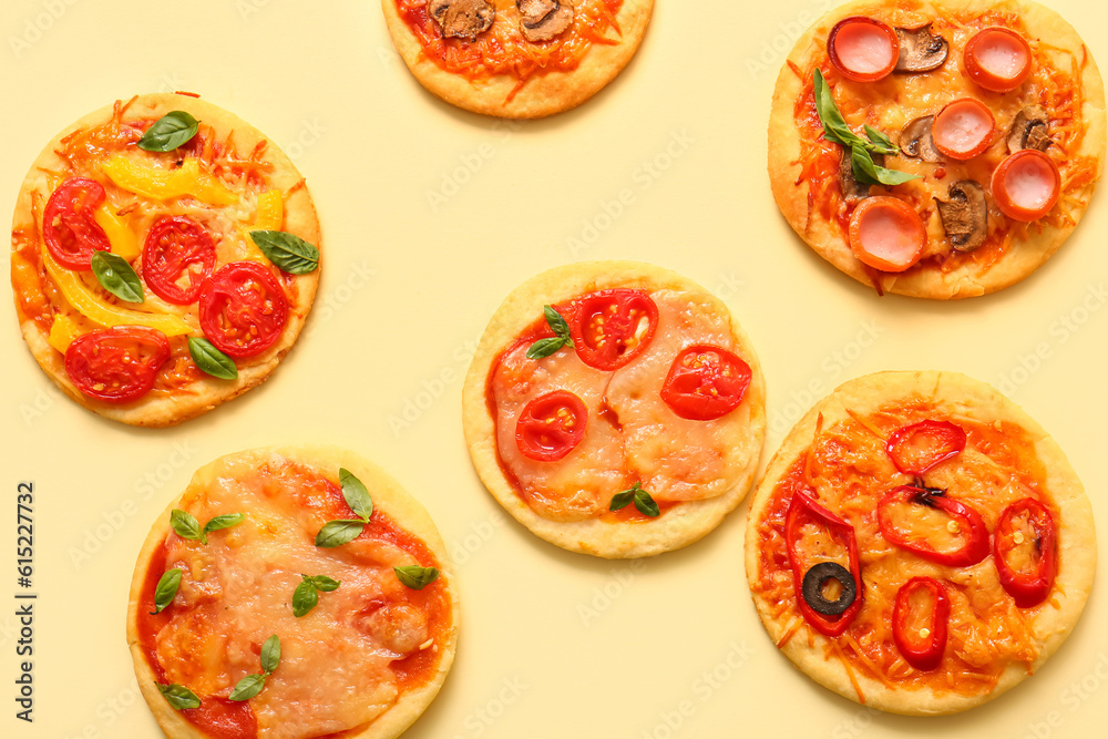 Different tasty mini pizzas on yellow background