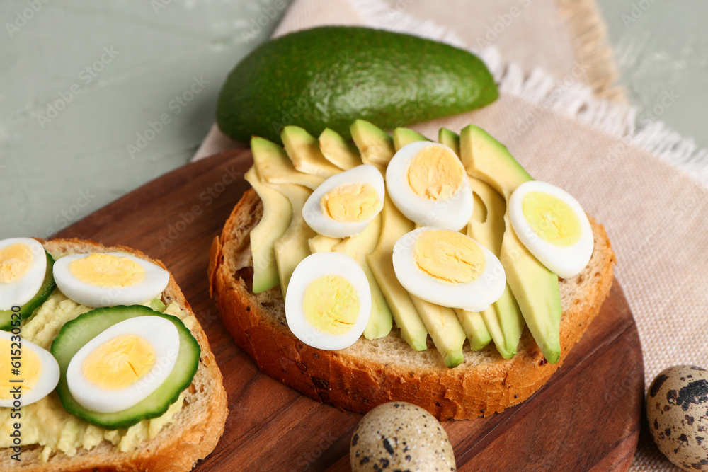 Tasty toasts with quail eggs, avocado and cucumber on color background, closeup