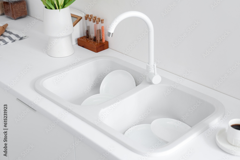 Clean plates in white kitchen sink, closeup