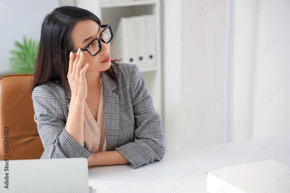 Beautiful Asian businesswoman in stylish eyeglasses in office