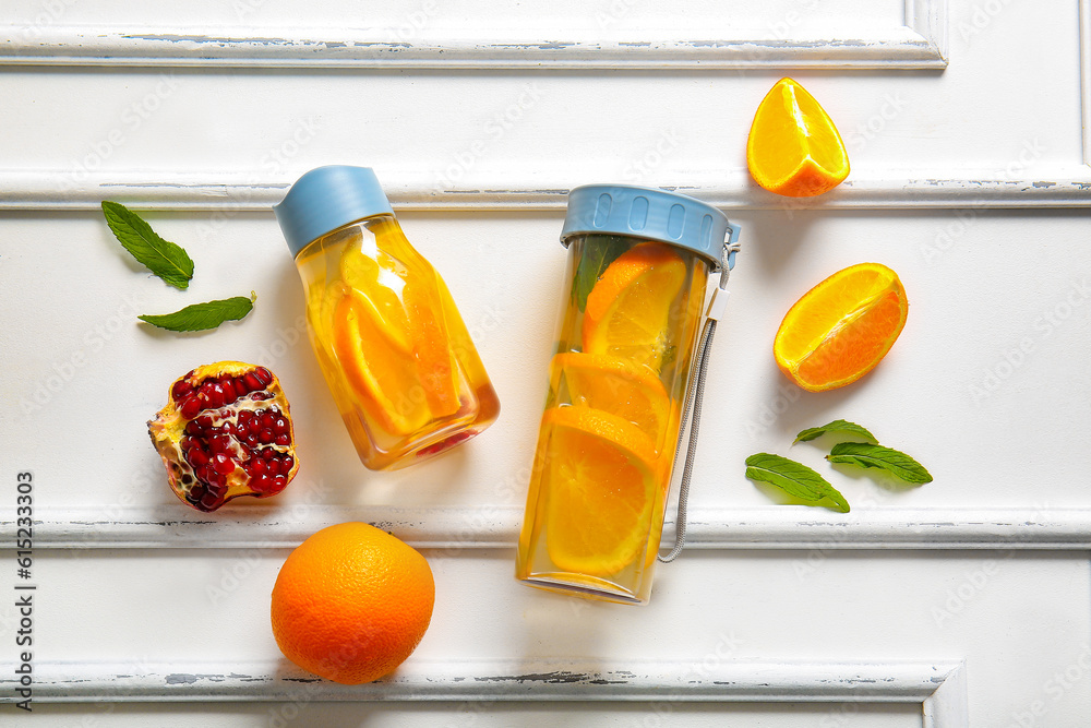 Sports bottles of infused water with orange slices on white background