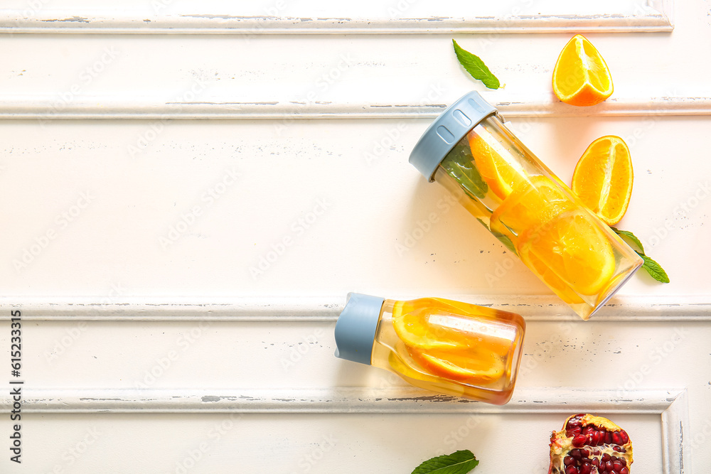 Sports bottles of infused water with orange slices on white background