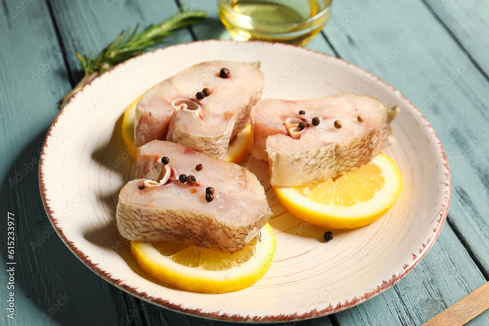 Pieces of raw codfish with lemon on green wooden background