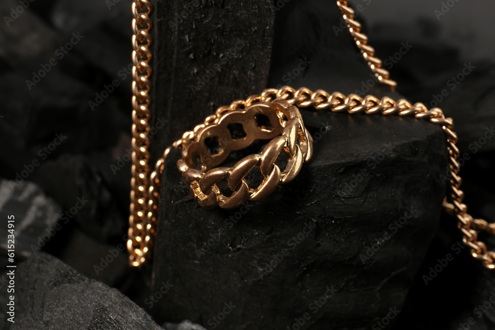 Beautiful chain necklace and ring on black charcoal, closeup