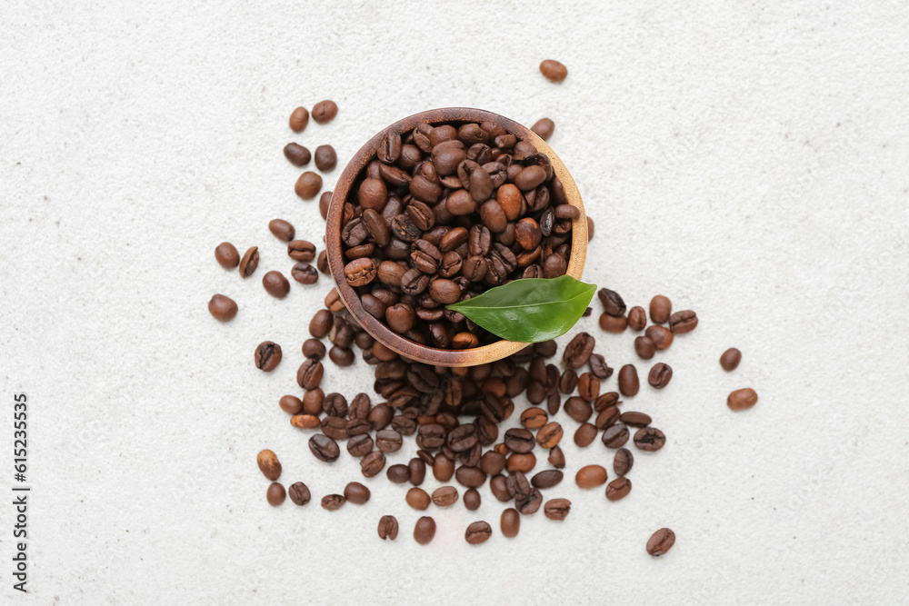 Bowl with coffee beans on light background