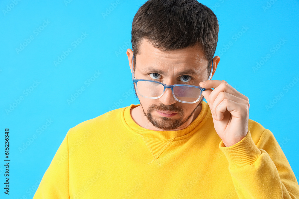 Handsome man in stylish eyeglasses on blue background, closeup