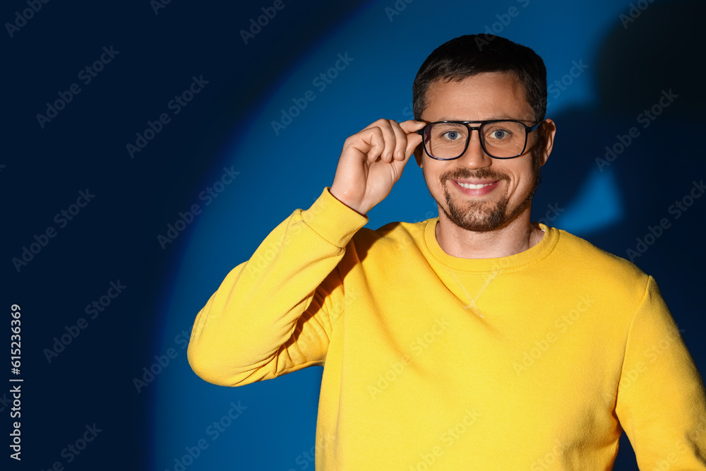 Handsome man in stylish eyeglasses on dark blue background