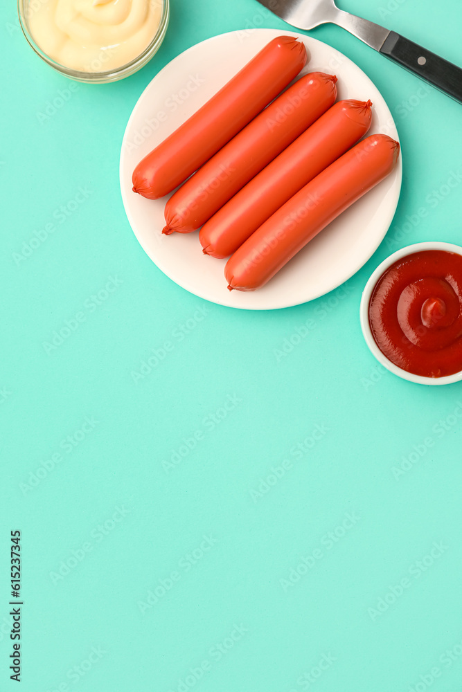 Plate with tasty thin sausages and sauces on blue background