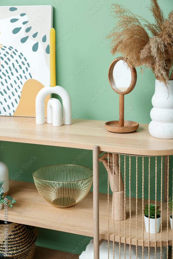 Shelving unit with painting, pampas grass and decor near green wall in room, closeup