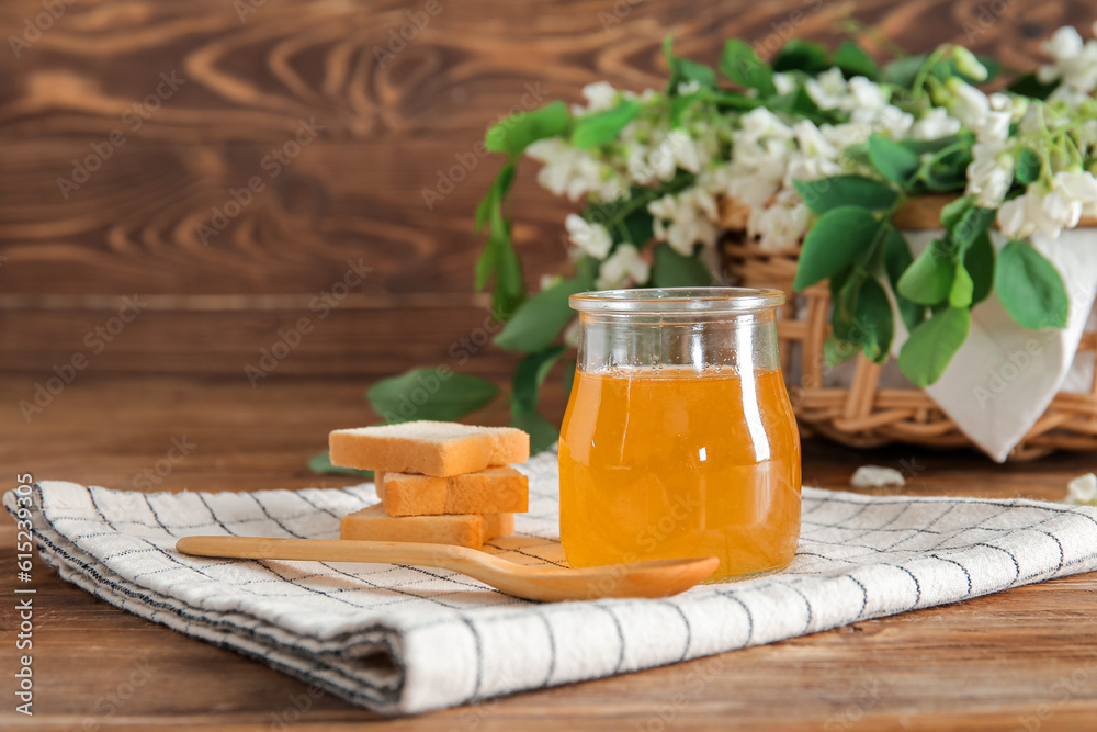 Composition with sweet honey, crackers and acacia flowers on wooden background, closeup