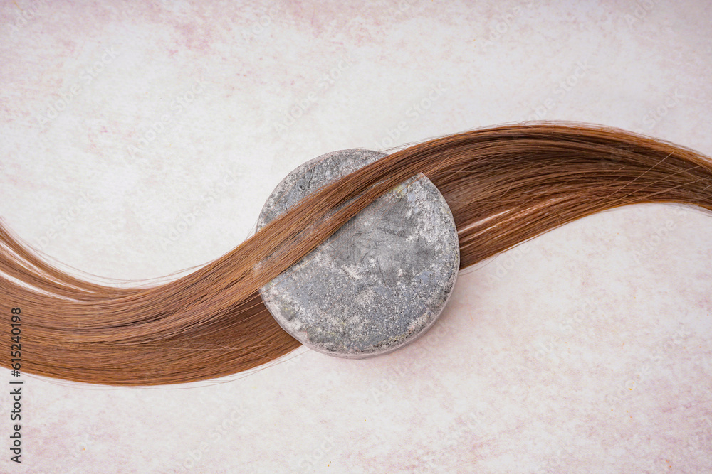 Handmade solid shampoo and brunette hair on light background