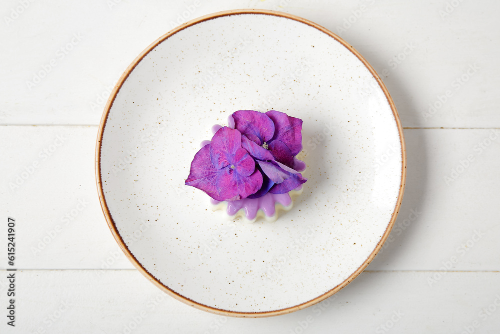 Plate of panna cotta with beautiful hydrangea flowers on white wooden table