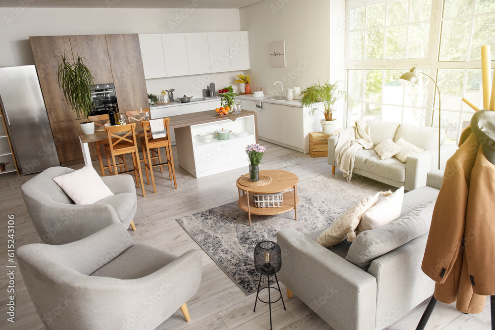 Interior of light open plan kitchen with coffee table, armchairs and sofas