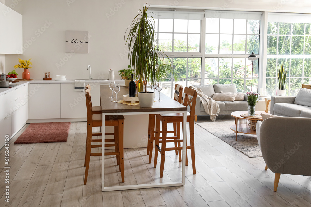 Island table with bottles of wine and glasses in interior of open plan kitchen