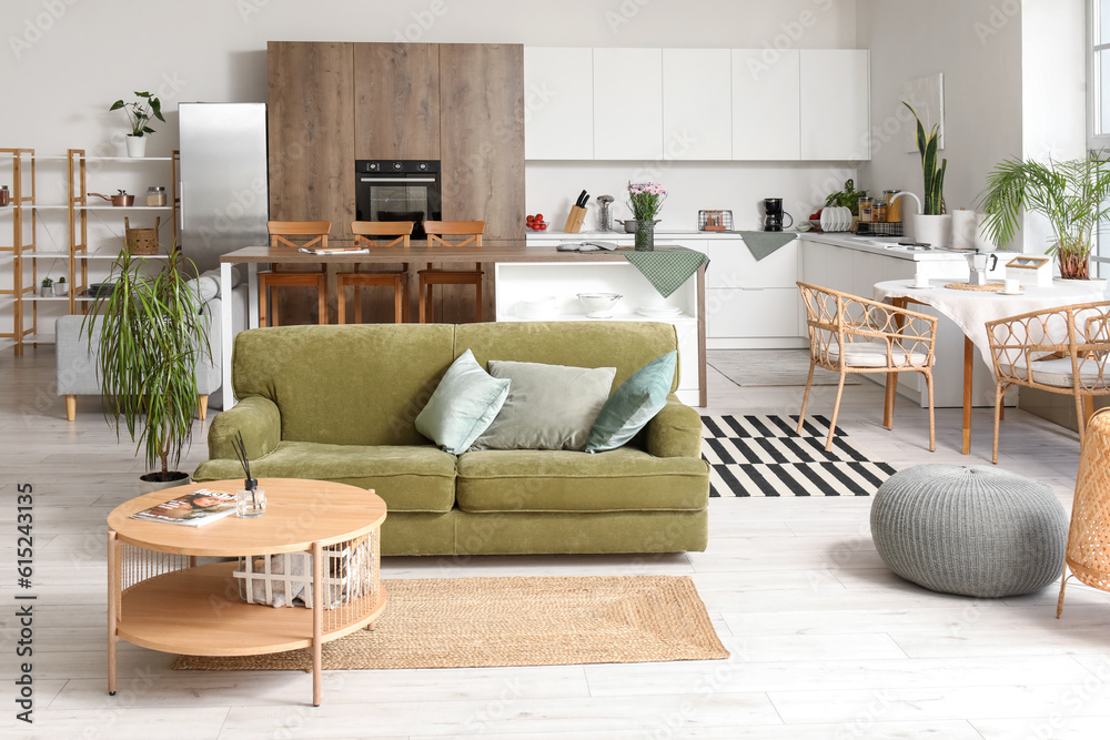 Interior of light open plan kitchen with green sofa and coffee table