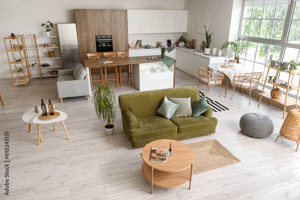 Interior of light open plan kitchen with green sofa and coffee table