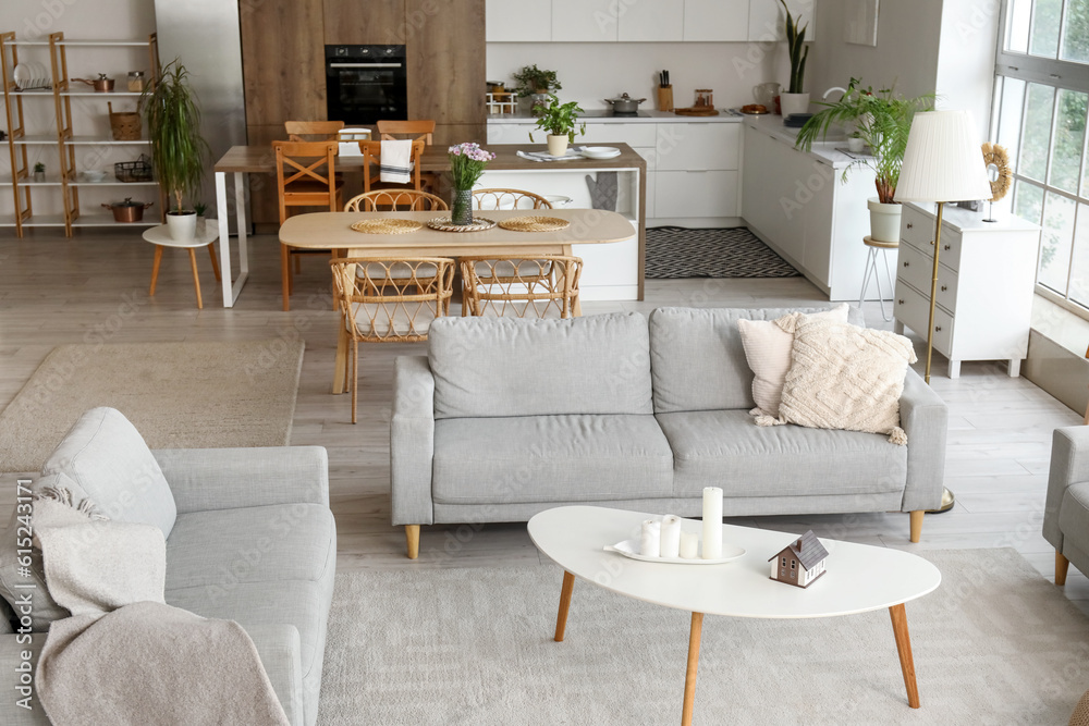 Interior of light open plan kitchen with grey sofas and coffee table