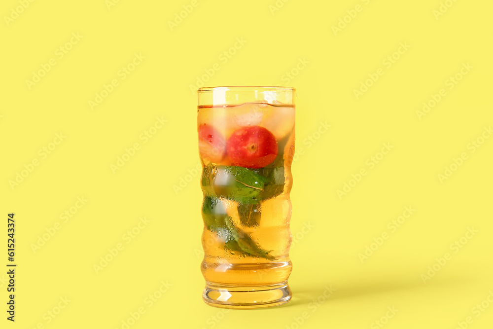 Glass of ice tea with strawberry and mint on yellow background