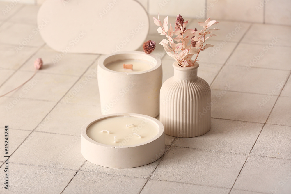 Holders with candles and reed diffuser on white tile background