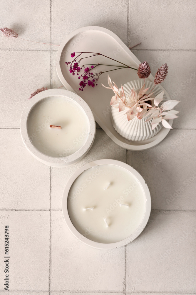 Holders with candles and reed diffuser on white tile background